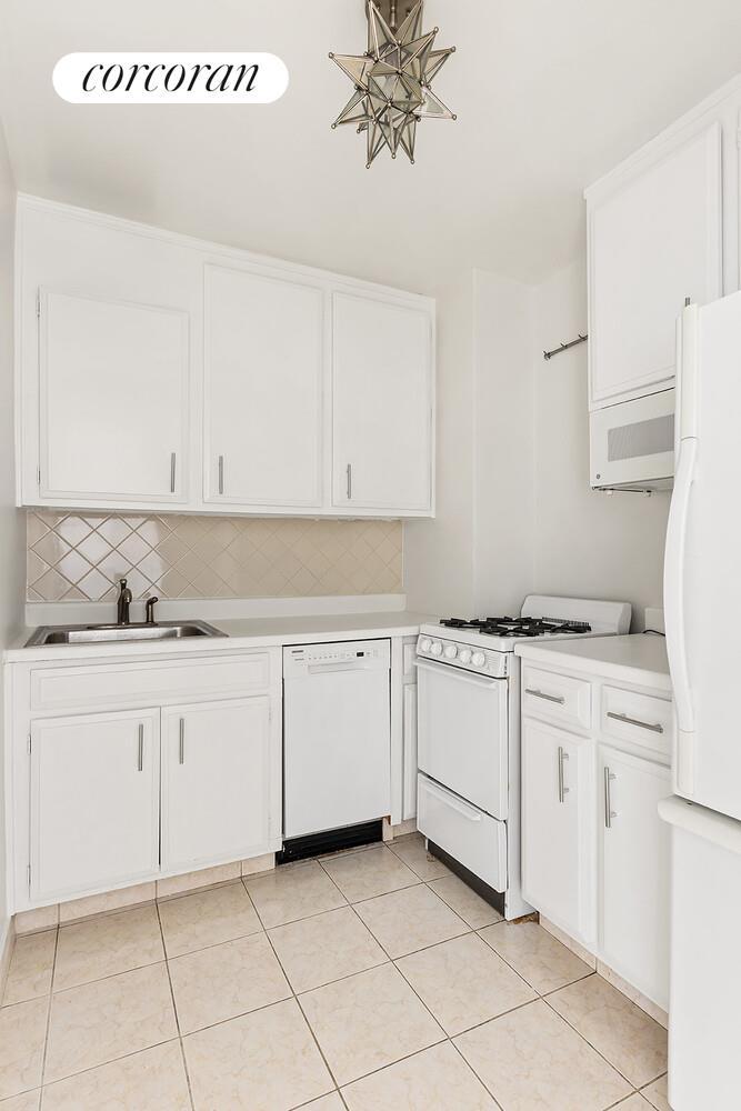 305 East 24th Street, Unit 5S Manhattan, NY 10010 - Photo 5 of 8 a kitchen with granite countertop white cabinets and white appliances