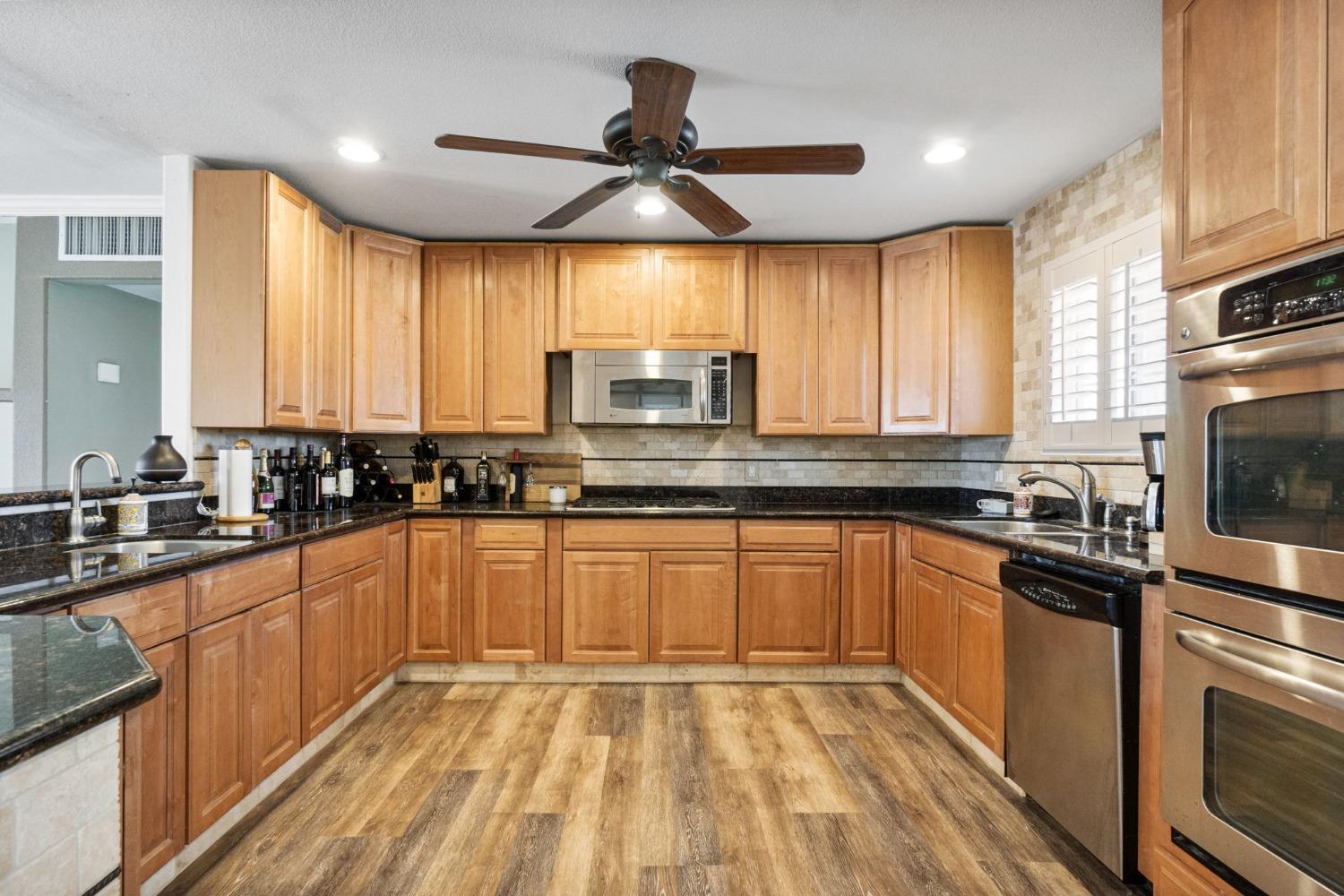 16972 Monreal Road Madera, CA 93636 - Photo 11 of 34 a kitchen with stainless steel appliances wooden cabinets a sink and a stove
