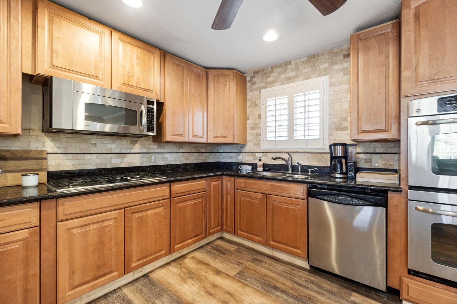 16972 Monreal Road Madera, CA 93636 - Photo 13 of 34 a kitchen with granite countertop white cabinets sink and stainless steel appliances