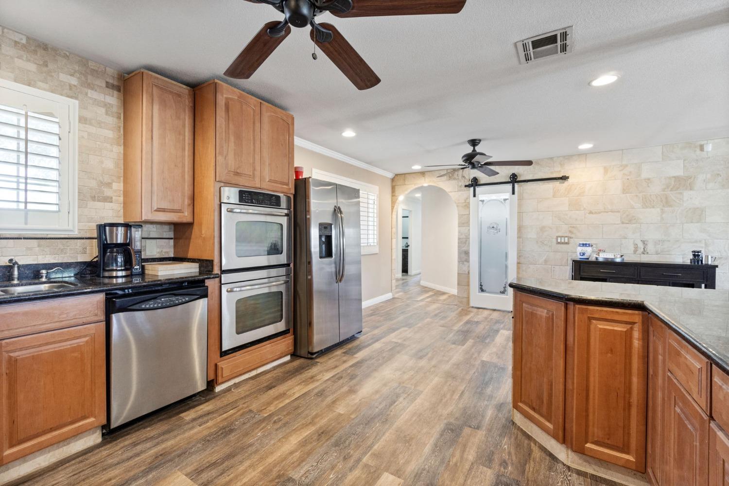 16972 Monreal Road Madera, CA 93636 - Photo 14 of 34 a kitchen with stainless steel appliances a refrigerator a sink and wooden cabinets
