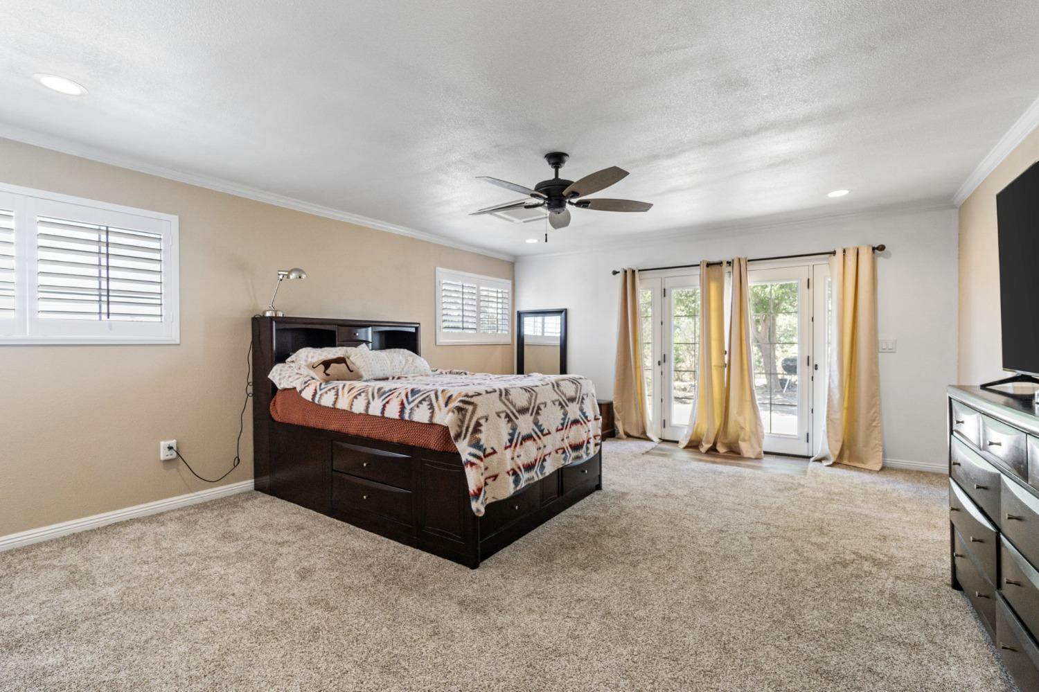 16972 Monreal Road Madera, CA 93636 - Photo 21 of 34 a spacious bedroom with a large bed and a chandelier