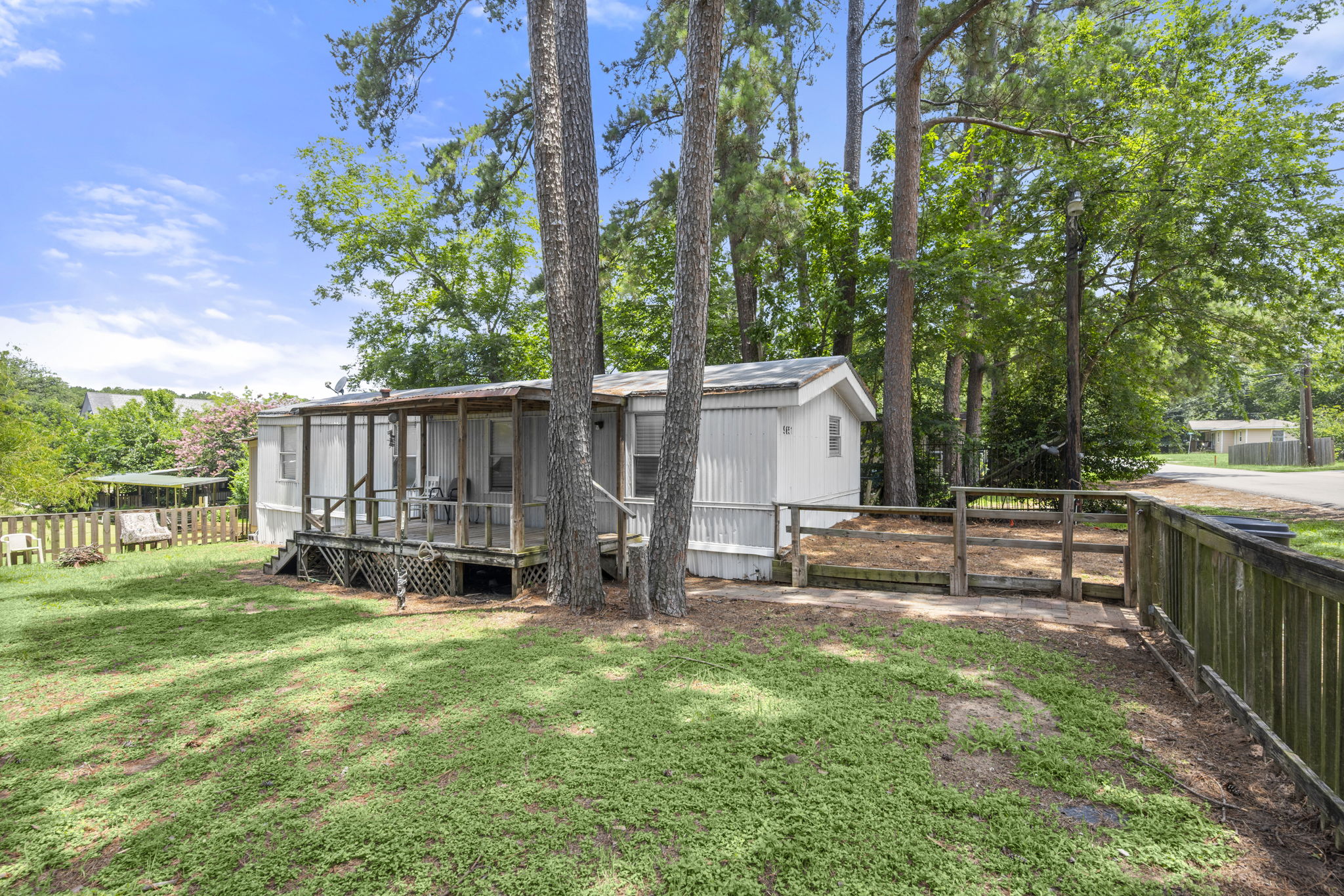 9649 Warm Spring Willis, TX 77318 - Photo 12 of 30 A quaint residential dwelling with an inviting porch and a verdant yard, nestled among mature trees.