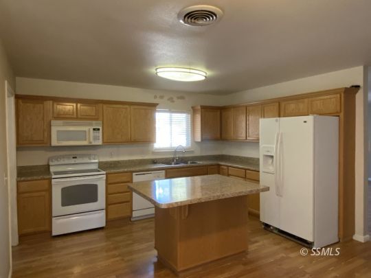 1037 West St George Avenue Ridgecrest, CA 93555 - Photo 2 of 8 a kitchen with stainless steel appliances granite countertop a sink a stove a refrigerator and island with wooden floor