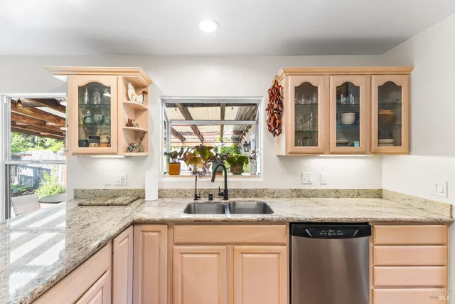 a front view of a kitchen with granite countertop a sink and a large window