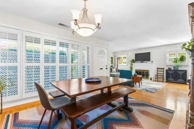 a dining room with wooden floor a chandelier a glass table and chairs