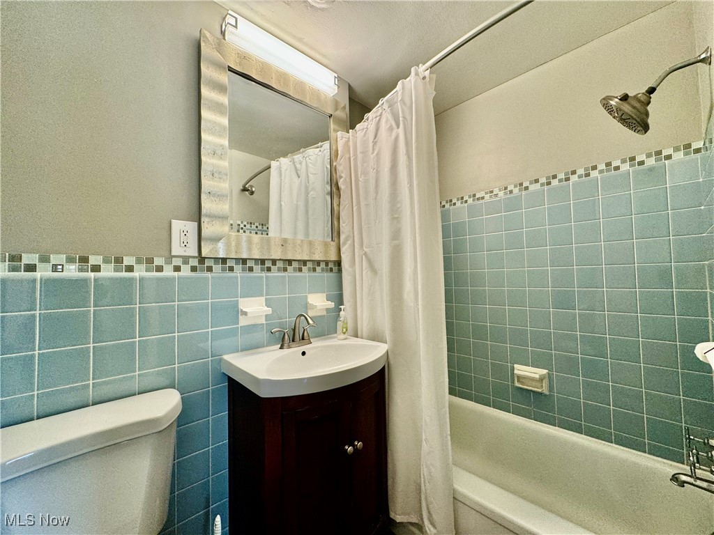 13805 Cedar Road, Unit 103C Cleveland, OH 44118 - Photo 14 of 18 Full bathroom featuring toilet, tile walls, shower / bath combo with shower curtain, decorative backsplash, and vanity