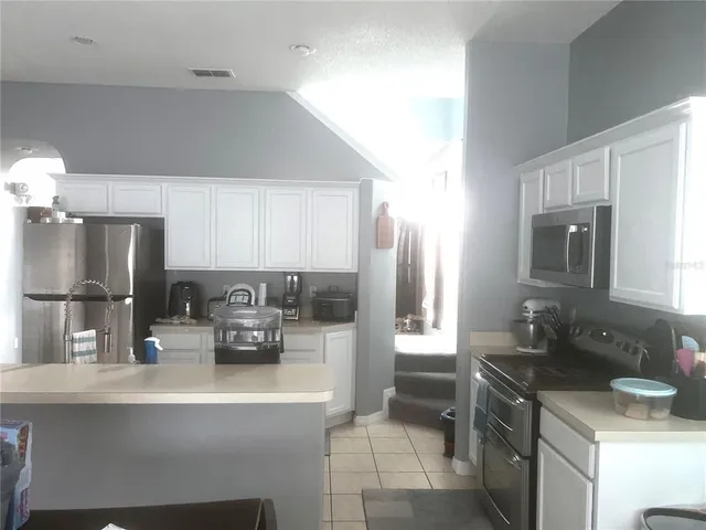 a kitchen with stainless steel appliances a sink a refrigerator a stove a microwave and island