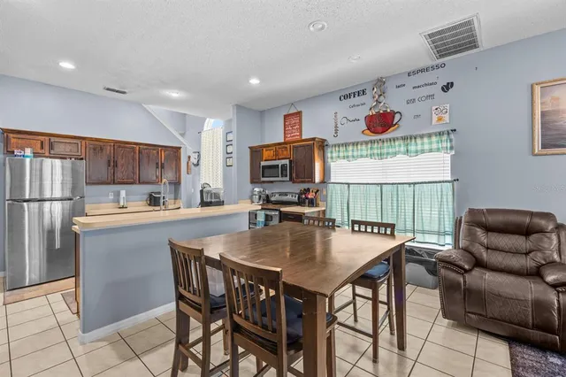 a view of kitchen with stainless steel appliances granite countertop dining table and chairs