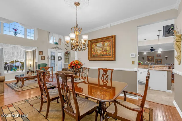 a view of a kitchen with kitchen island a stove a refrigerator a sink dishwasher with a dining table and chairs with wooden floor