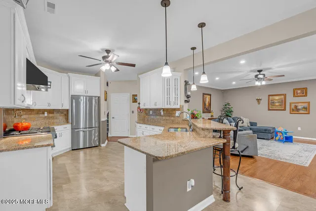 a room with stainless steel appliances kitchen island granite countertop furniture and a view of kitchen
