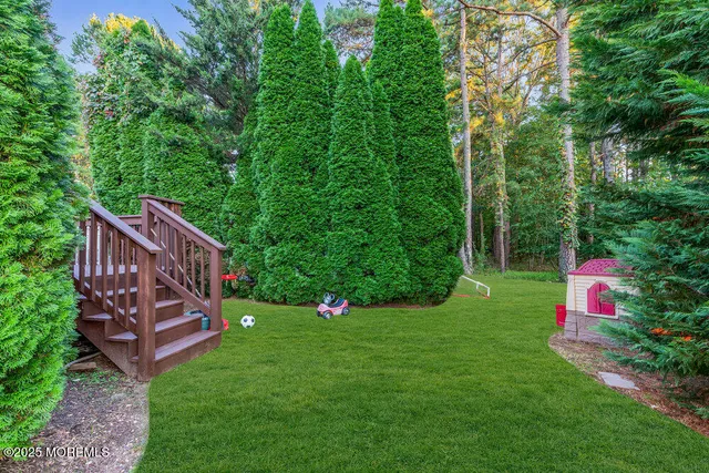 a view of a white house with a big yard and large trees