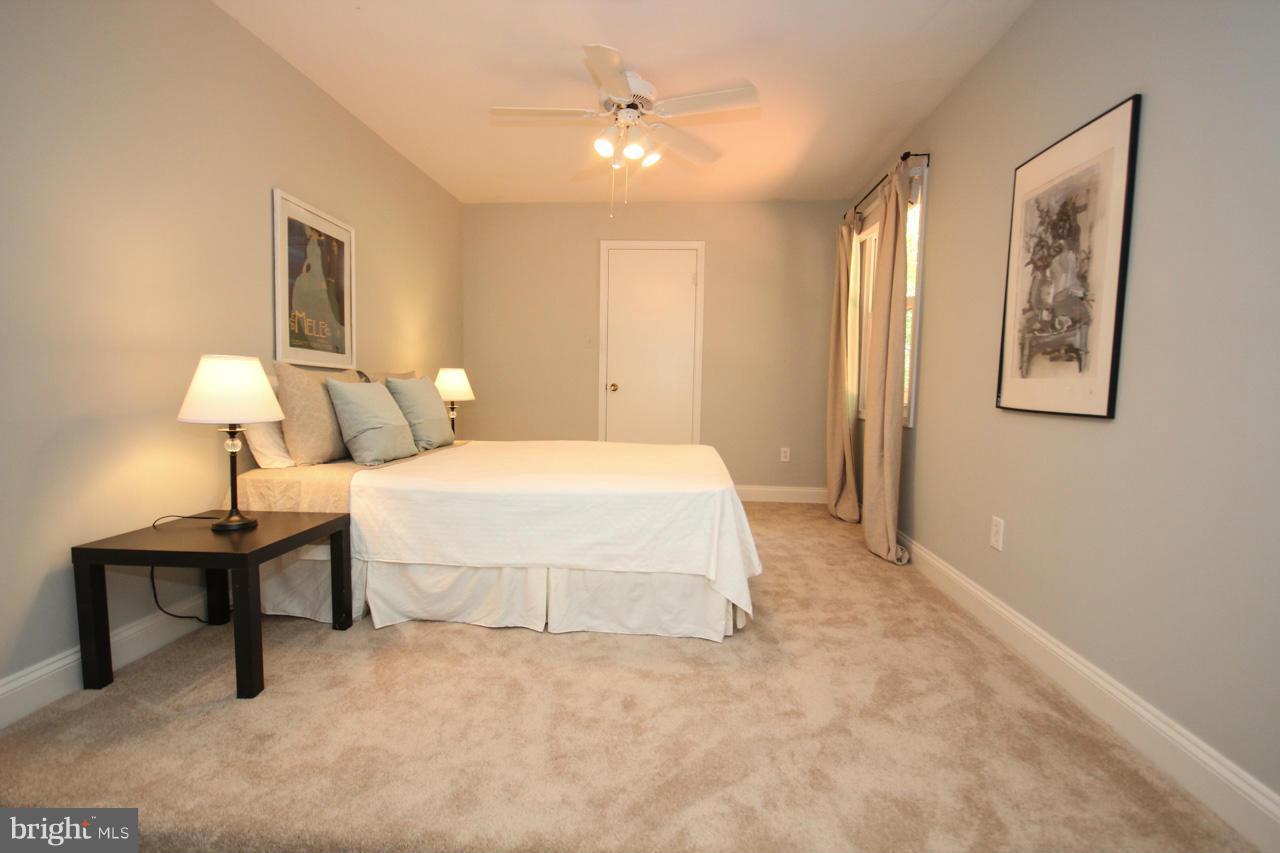 14305 Piccadilly Road Silver Spring, MD 20906 - Photo 21 of 30 a spacious bedroom with a bed and a lamp on table