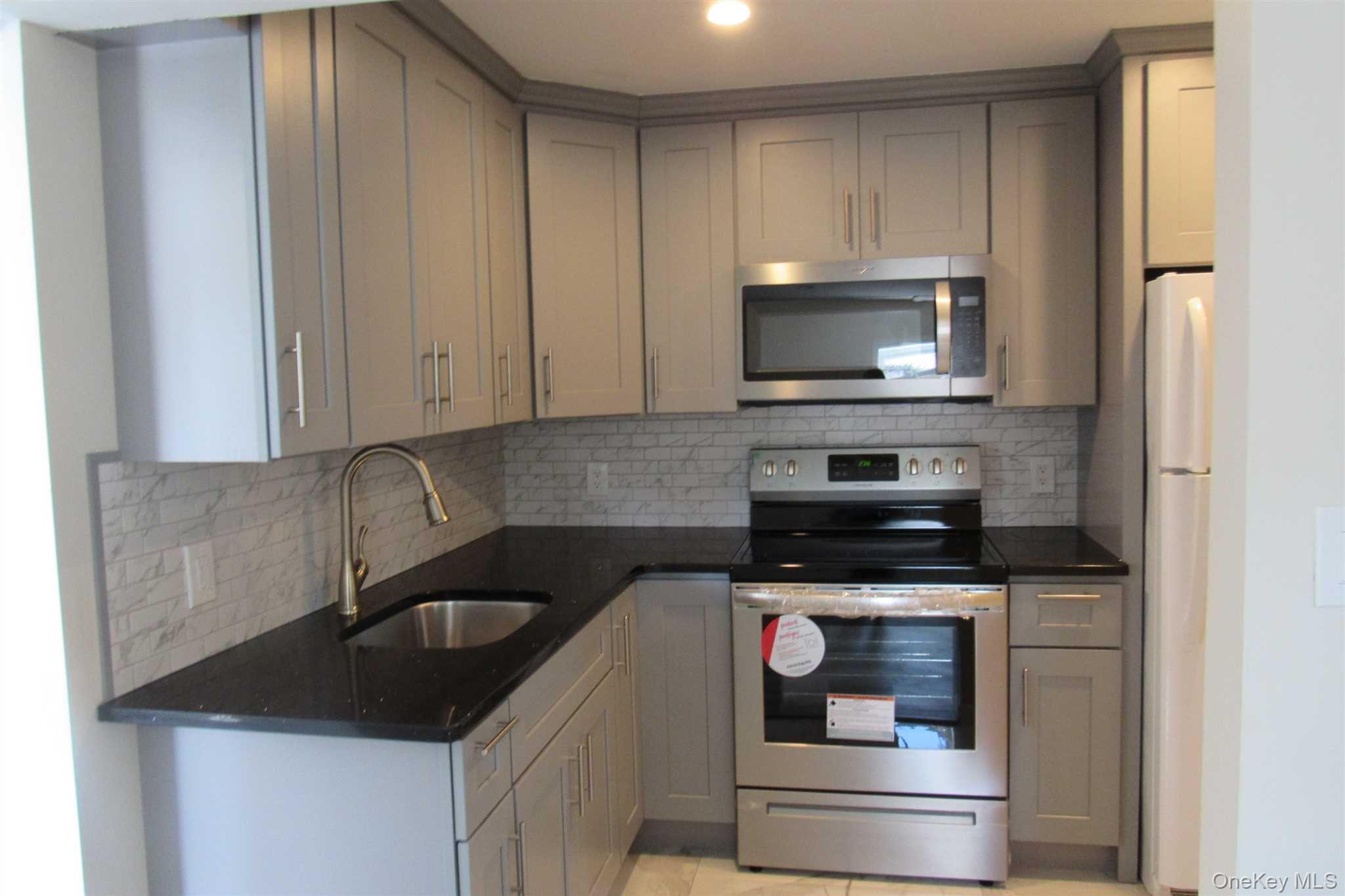 1425 Highway 82, Unit B Hopewell Junction, NY 12533 - Photo 8 of 19 a kitchen with granite countertop white cabinets and stainless steel appliances