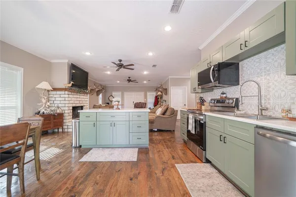 a kitchen with stainless steel appliances granite countertop a refrigerator a sink dishwasher a dining table and chairs with wooden floor