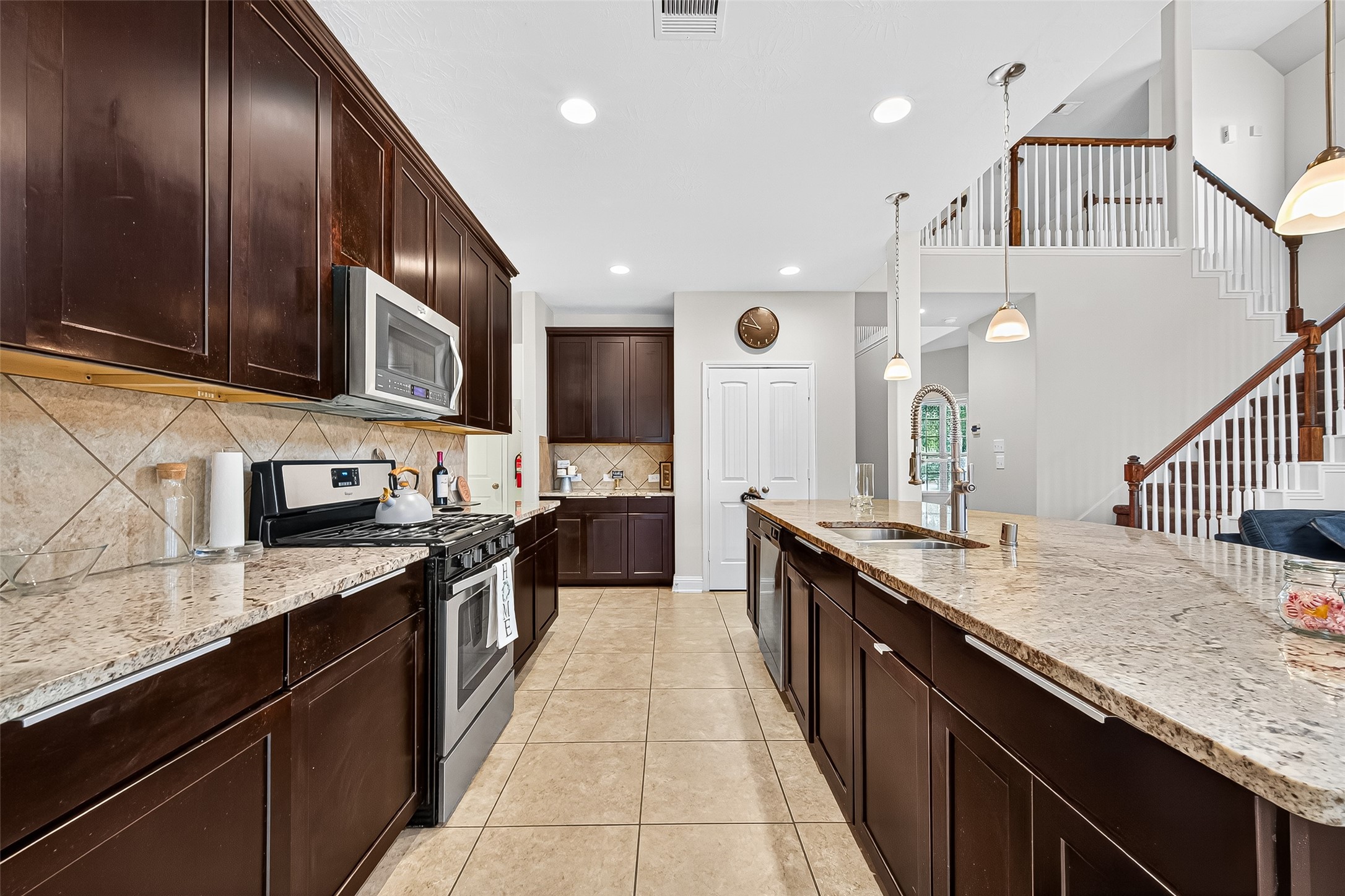 8107 Lockridge Terrace Lane Cypress, TX 77433 - Photo 21 of 50 This beautifully appointed kitchen is both elegant and functional, featuring rich espresso cabinetry, granite countertops, and a generous island perfect for gatherings. Under-cabinet lighting adds warmth and highlights the detailed tile backsplash. The double-door pantry offers ample storage, keeping everything within reach and organized—an entertainer’s dream and a chef’s delight.