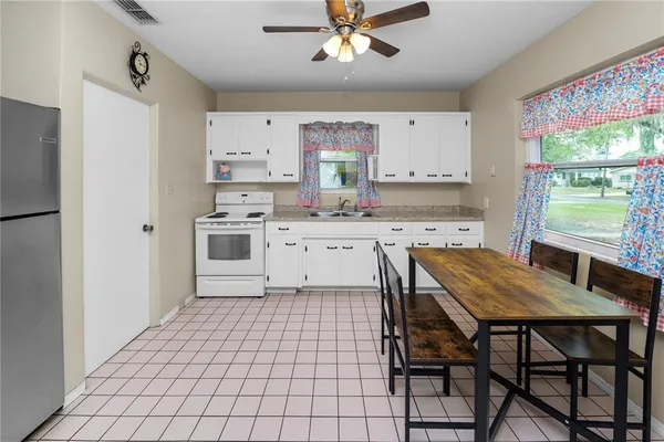 a kitchen with stainless steel appliances a white table chairs and a refrigerator