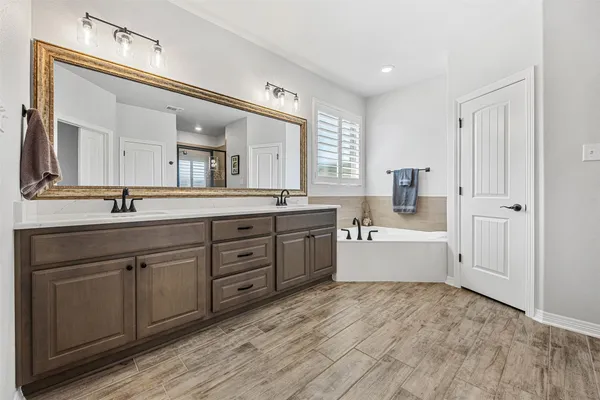 a large white bathroom with a double vanity sink a mirror and a bathtub