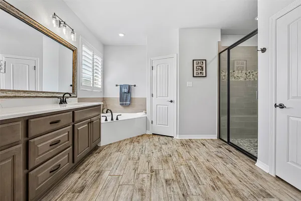 a spacious bathroom with a shower a sink and a mirror