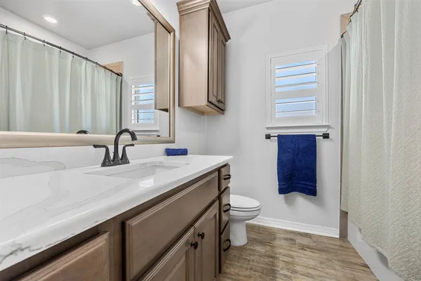 a bathroom with a granite countertop sink a toilet and a mirror