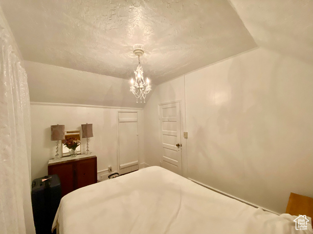 350 West Main Street Emery, UT 84522 - Photo 11 of 28 Bedroom featuring vaulted ceiling, a textured ceiling, and a chandelier