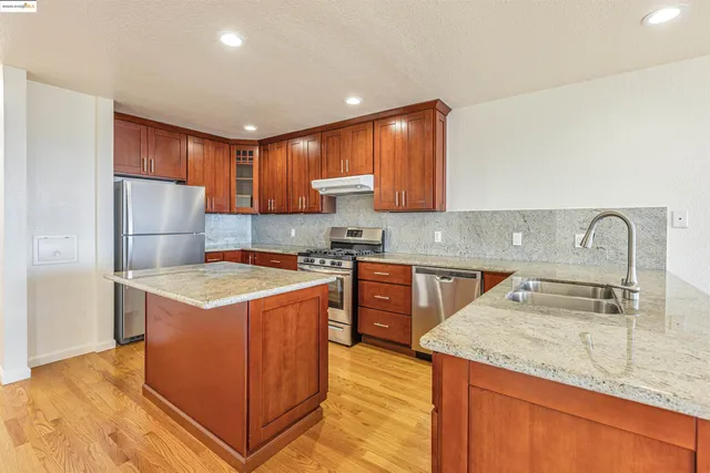 a kitchen with stainless steel appliances granite countertop a sink stove and refrigerator