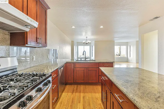 a kitchen with stainless steel appliances granite countertop a sink stove and cabinets