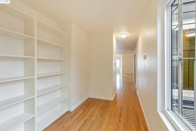 a view of an empty room with a window and wooden floor