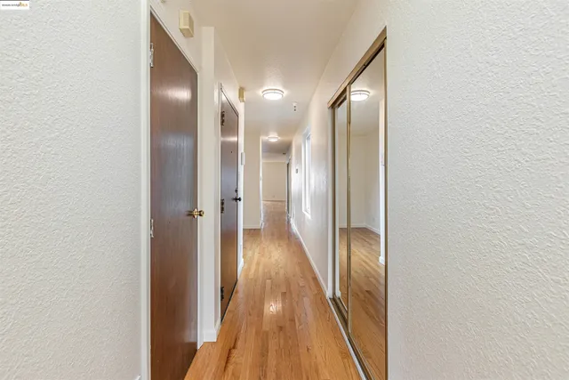 a view of a room with wooden floor and kitchen view