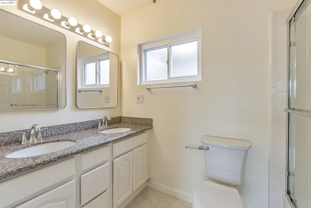 a bathroom with a granite countertop toilet sink and mirror