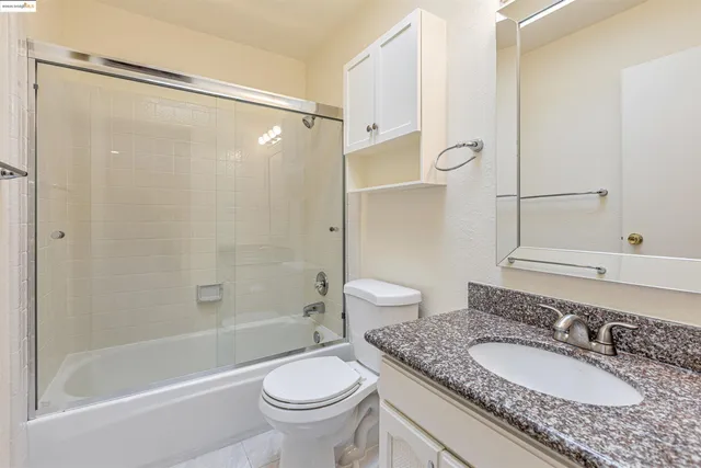 a bathroom with a granite countertop sink toilet mirror and shower