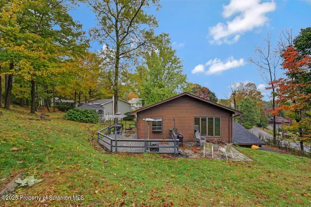 a white house with a big yard plants and large trees