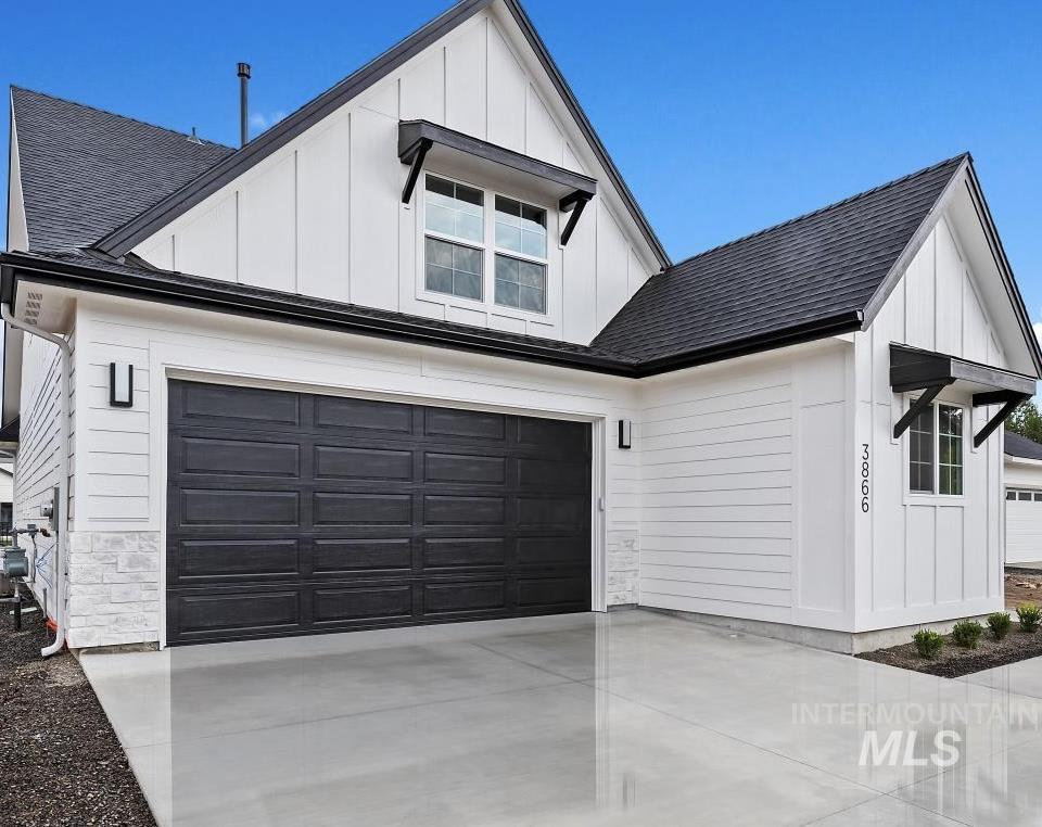 Modern farmhouse style home featuring roof with shingles, board and batten siding, and concrete driveway
