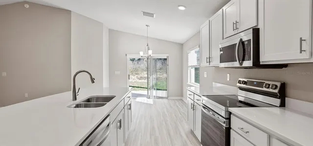 a kitchen with stainless steel appliances a sink a stove top oven a counter space and cabinets