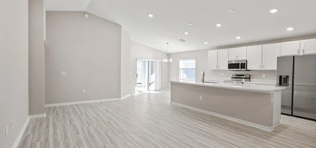 a kitchen with stainless steel appliances granite countertop a refrigerator a sink dishwasher a stove and white cabinets with wooden floor