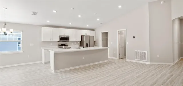 a large kitchen with kitchen island a sink wooden floor and a refrigerator