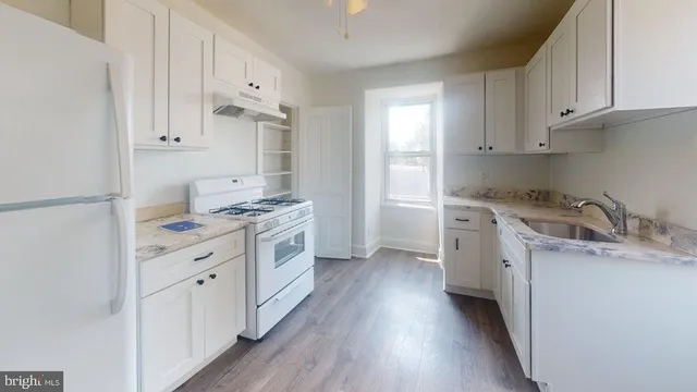 a kitchen with granite countertop a sink stove and cabinets