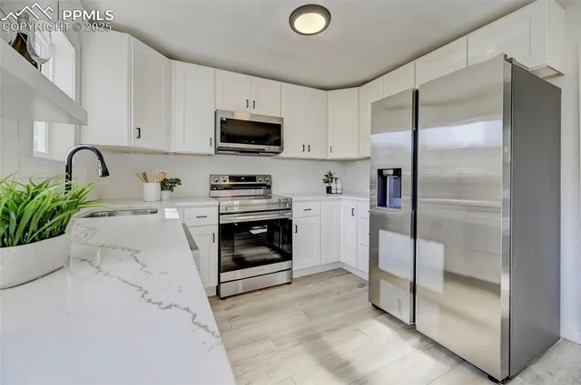 a kitchen with stainless steel appliances a refrigerator sink and white cabinets