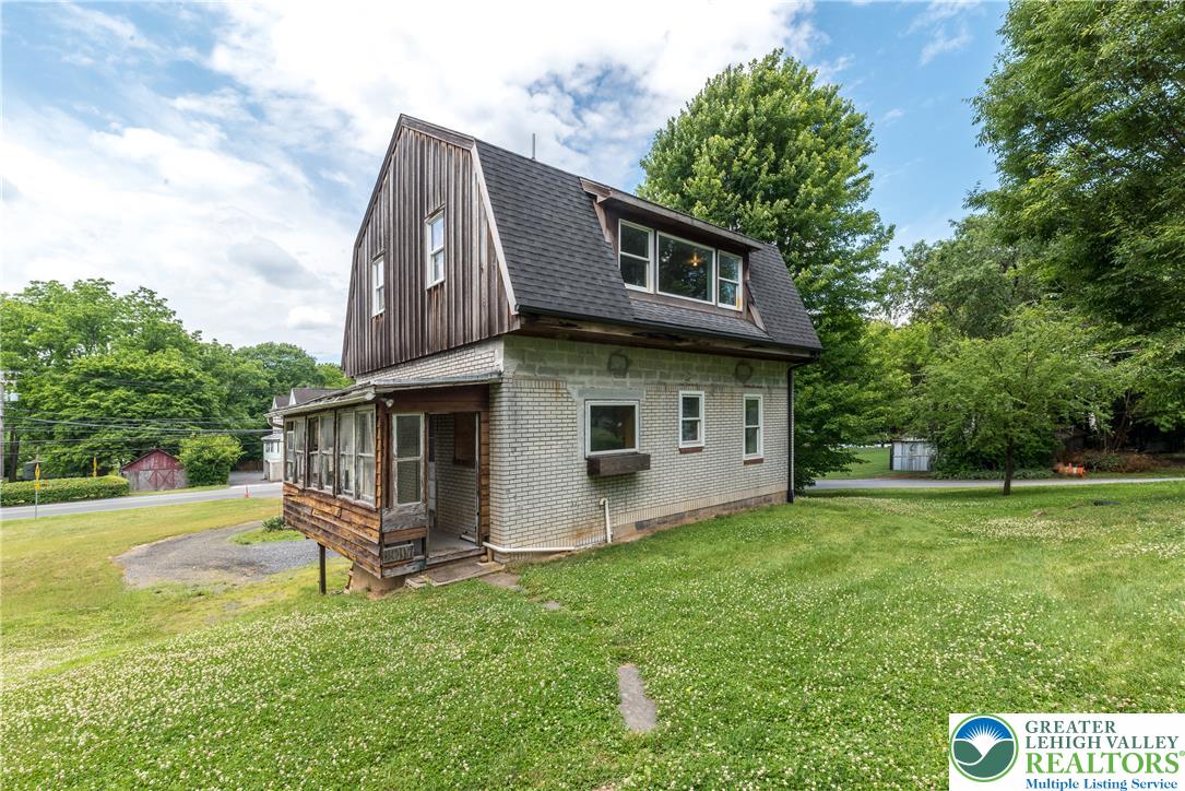 1815 Leithsville Road Hellertown, PA 18055 - Photo 33 of 38 A charming gambrel roofed home with wood siding and a sun porch, nestled in a verdant setting.