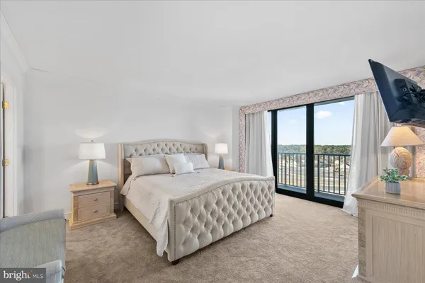 a bedroom with a bed lamp and a large window