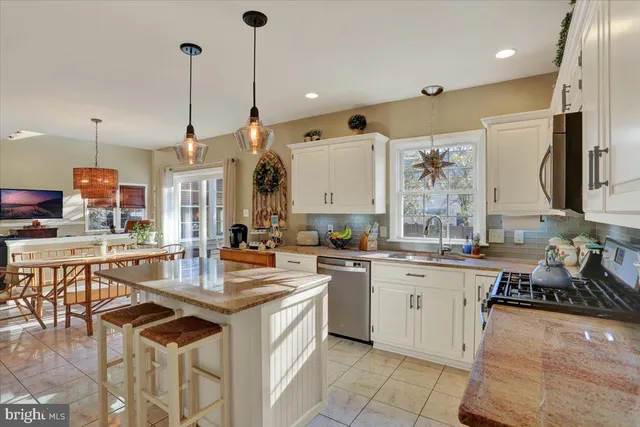 a open kitchen with stainless steel appliances granite countertop a refrigerator a sink dishwasher a stove and white cabinets with wooden floor