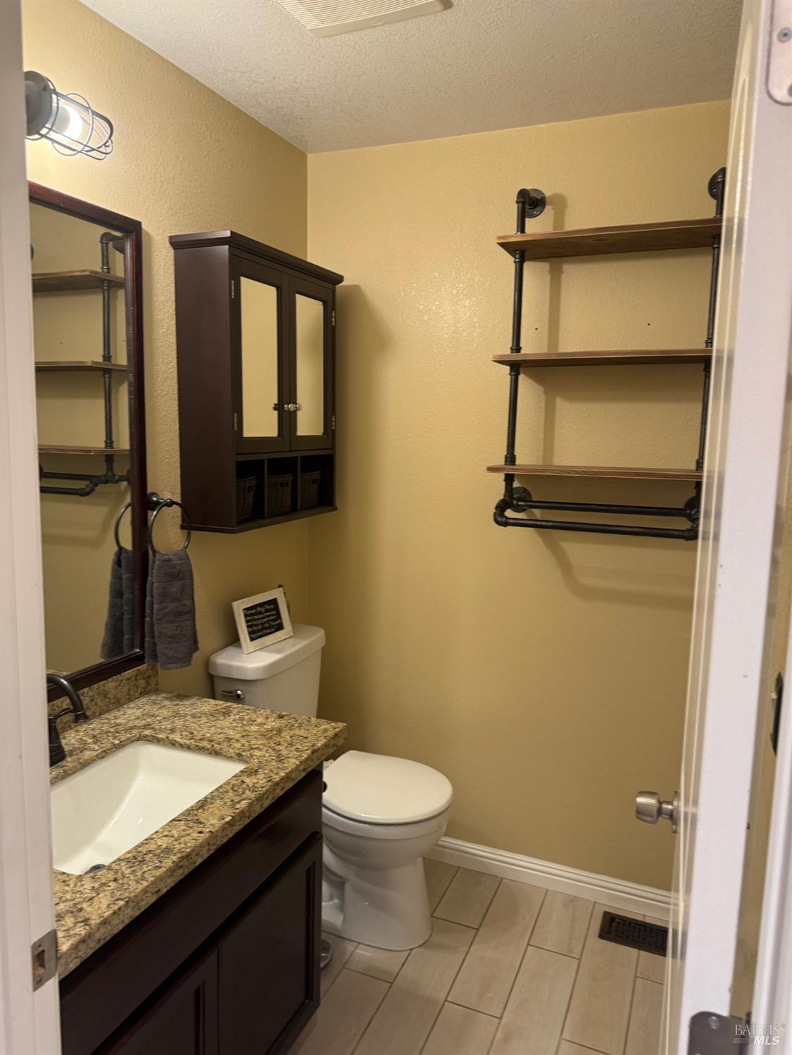 2813 Beth Court Santa Rosa, CA 95403 - Photo 22 of 24 a bathroom with a granite countertop sink toilet and mirror