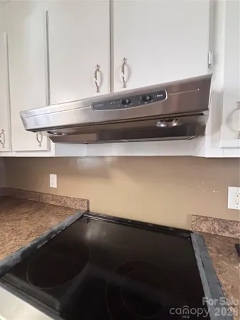 a kitchen with a stove and white cabinets