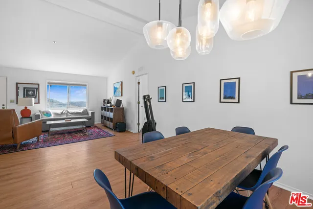 a dining room with wooden floor a chandelier a wooden table and chairs