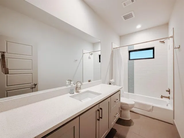a bathroom with a double vanity sink a toilet and shower