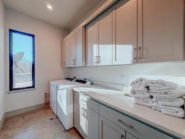a utility room with stainless steel appliances granite countertop a sink a stove and cabinets