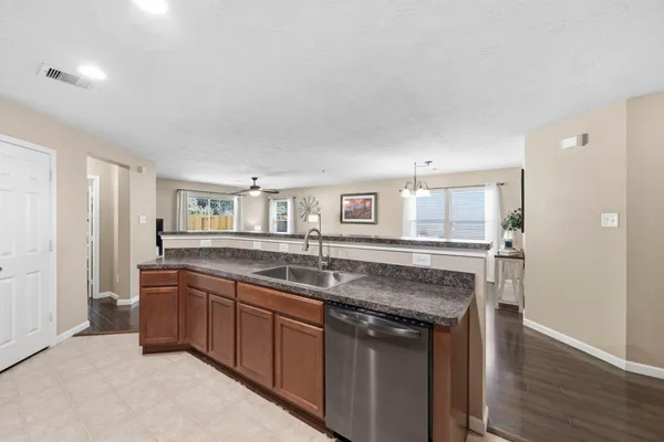 a view of kitchen with stainless steel appliances granite countertop a refrigerator a sink dishwasher and a oven with wooden floor