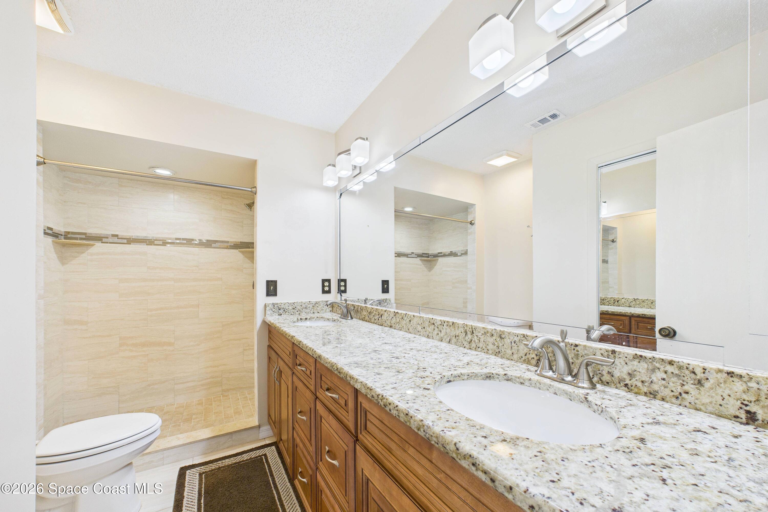 204 Country Club Drive Melbourne, FL 32940 - Photo 56 of 63 a bathroom with a granite countertop sink a toilet a mirror and shower