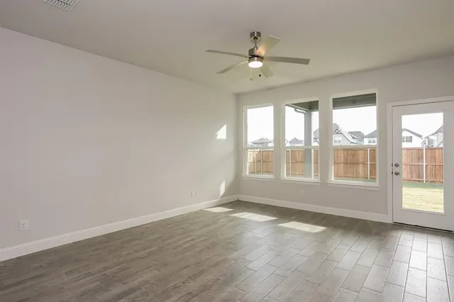 a view of an empty room with a window and wooden floor