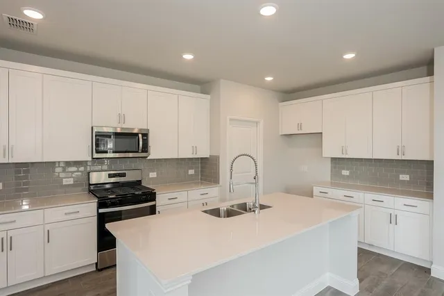 a view of kitchen with refrigerator stove and wooden floor