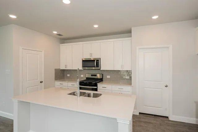 a kitchen with sink a microwave and cabinets